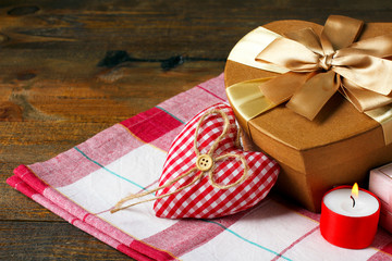 Decorative heart for Valentine's day with candle and gift on fabric on wooden background