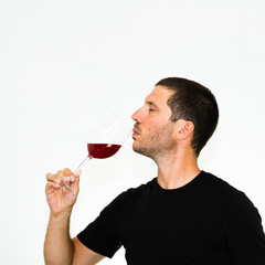 close-up of young caucasian man tasting a glass of red wine- isolated on white background