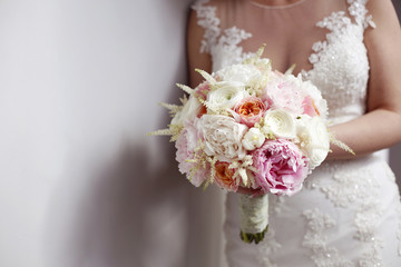 Bride holding colorful bridal bouquet next to white wall