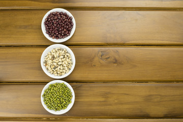 Black eye peas, mung bean and adzuki beans in white bowl on wooden background