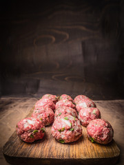 raw minced meat balls with herbs and onions on a vintage cutting board  close up