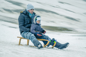 Fototapeta na wymiar man rolls the child on a sled