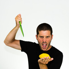 close-up of aggressive young caucasian chef trying to cut a lemon with a plastic knife - isolated on white background