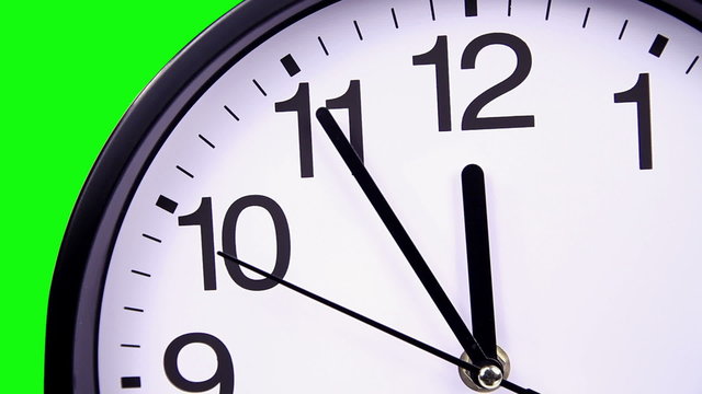 Wall clock on a green background 23:55 close-up hours