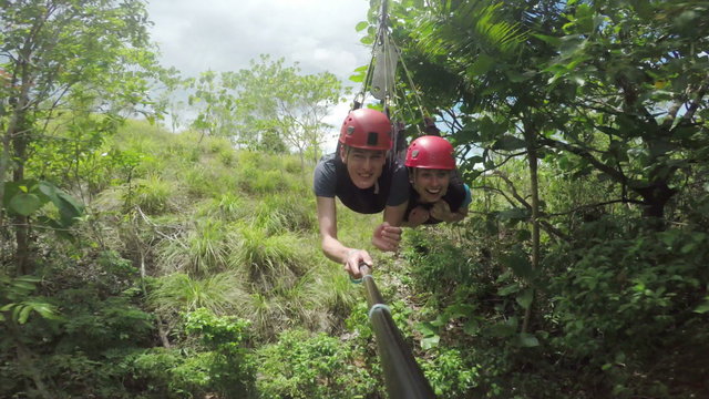 Great footage of a happy couple sliding down a zip line in tandem, over a canyon and into the woods. Part two, filmed of a selfiestick. 
