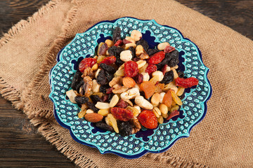 Dried fruits. Hazelnuts, almonds, cashews, apricots, cherries, walnuts, raisins. Background - Turkish plate and burlap. Vintage.