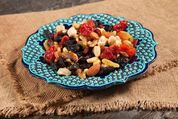 Dried fruits. Hazelnuts, almonds, cashews, apricots, cherries, walnuts, raisins. Background - Turkish plate and burlap. Vintage.