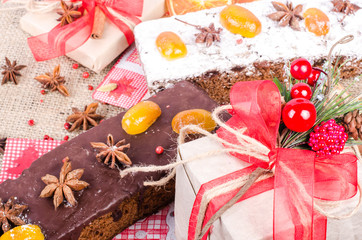 Chocolate spices cake, star anise and dried fruits, packed gifts with red tapes on sackcloth, canvas. Sweet frame. Top view