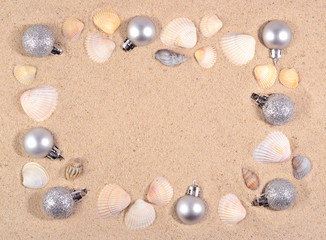 Fototapeta na wymiar Silver Christmas decorations and seashells on a beach sand