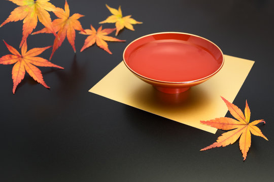 vermilion lacquer coated sake cup and maple leaves. vermilion sake cups are used for festive meals, especially for New Year celebration or wedding ceremonies.