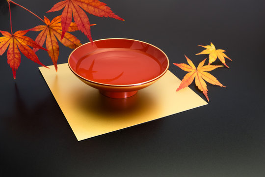 vermilion lacquer coated sake cup and maple leaves. vermilion sake cups are used for festive meals, especially for New Year celebration or wedding ceremonies.