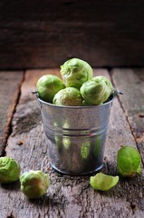 Organic Brussels sprouts in an aluminum bucket on old wooden table, rustic style 