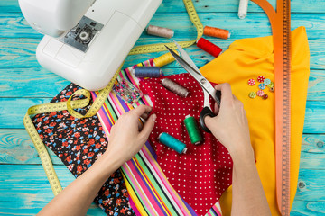 Creating a new fashion. Sewing Process - Women's hands behind her sewing. Sewing machine with many...