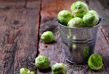 Organic Brussels sprouts in an aluminum bucket on old wooden table, rustic style