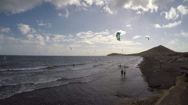 many surfer on ocean - kite surfing and wind surfing beach, medano