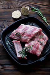 Cast-iron grill with fresh pork ribs and seasonings, studio shot