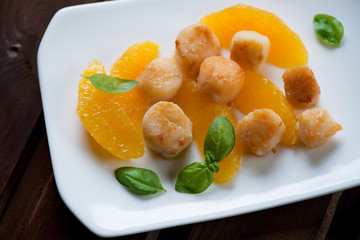 Roasted sea scallops served with orange filet and basil, closeup
