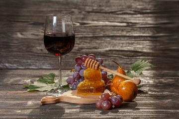 Glass of red wine, honeycomb, grapes on a wooden background. Selective focus.