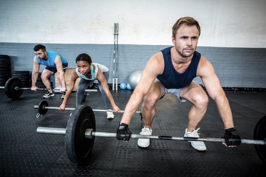 Three muscular athletes liftings barbells
