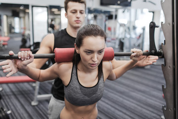 man and woman with barbell flexing muscles in gym