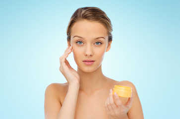 young woman applying cream to her face