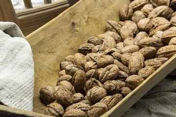 Viele frische Walnüsse in einer Holzschale auf einem Bauernstuhl mit einem Leinentuch