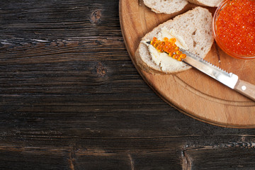 Obraz na płótnie Canvas Bread and red caviar on a wooden background.