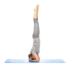 woman making yoga in headstand pose on mat