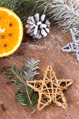 Christmas backgrounf with orange, cloves, stars and fir branches on wooden background