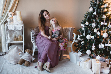 Mother and daughter near the Christmas tree, hugging, preparation for Christmas, decoration, decor, lifestyle, family, family values