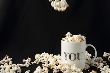 White jar with popcorn on black background
