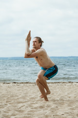 Fototapeta premium Man practices yoga on a sandy beach