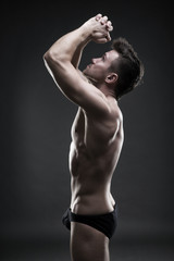 Fototapeta na wymiar Handsome muscular bodybuilder posing on gray background. Low key studio shot