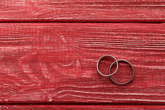 Silver Wedding Rings On A Red Wooden Table