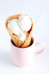 Waffle cone with white ice cream on wooden table