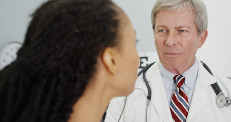 Senior doctor talking to adult woman in the office