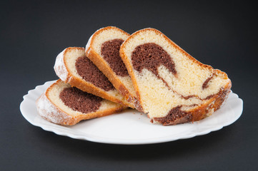 Gugelhupf on a plate on black background