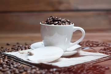 White cup and coffee grains on a wooden surface
