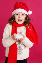 Little girl in santa hat is holding fake snow 