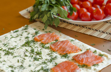 Slices of fresh salmon on a piece of pita with cherry tomatoes. Cooking