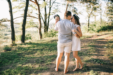 Fototapeta premium Happy family of mother father and lovely daughter in sunset light. 