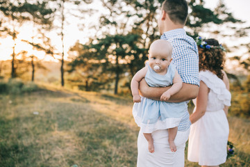 Fototapeta premium Happy family of mother father and lovely daughter in sunset light. 