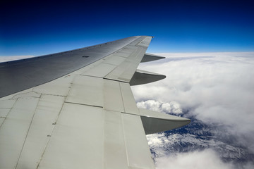 Fototapeta na wymiar Airplane wing with view of Salt Lake City mountains through the clouds 