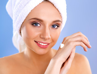 Young woman  putting cream on her hand Isolated on gray background