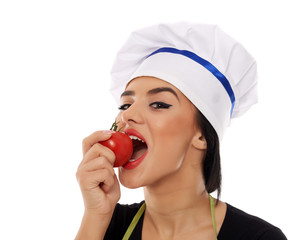 Woman cook eating a fresh tomato