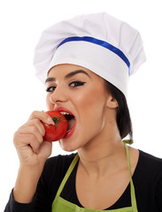 Woman cook eating a fresh tomato