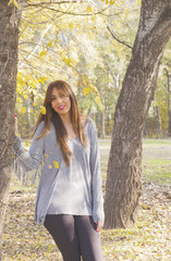 Attractive young woman leaning against a tree