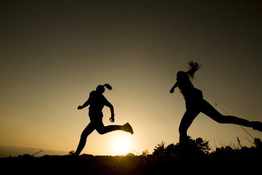 silhouette of two young women who exercise at sunset