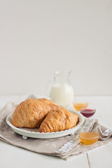 Romantic breakfast with croissant, coffee, milk, honey and jam on the table