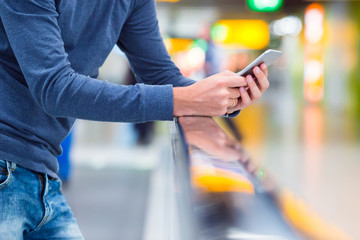 Man with backpack holding cell phone at airport waiting the flight